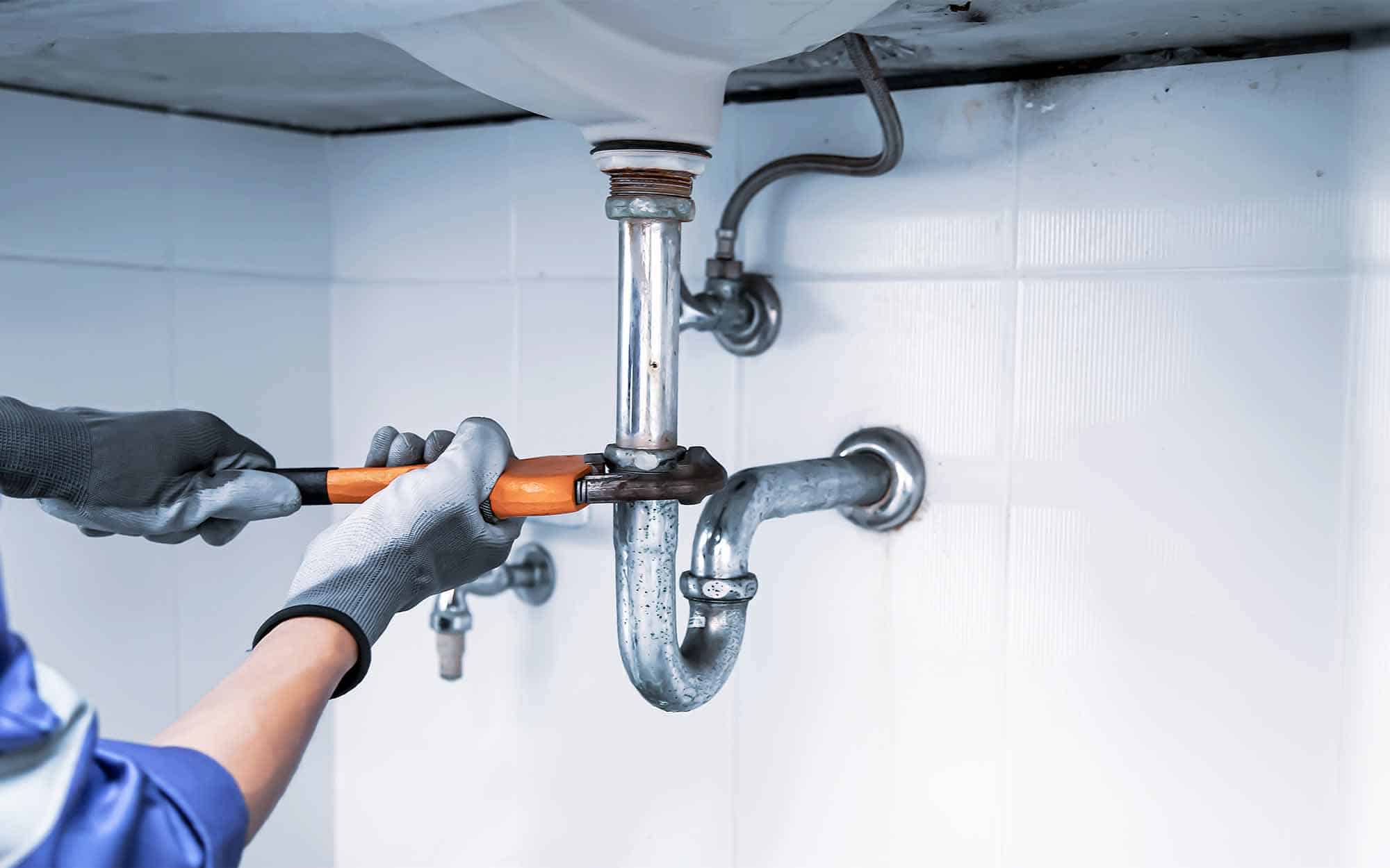 Technician-plumber-using-a-wrench-to-repair-a-water-pipe-under-the-sin